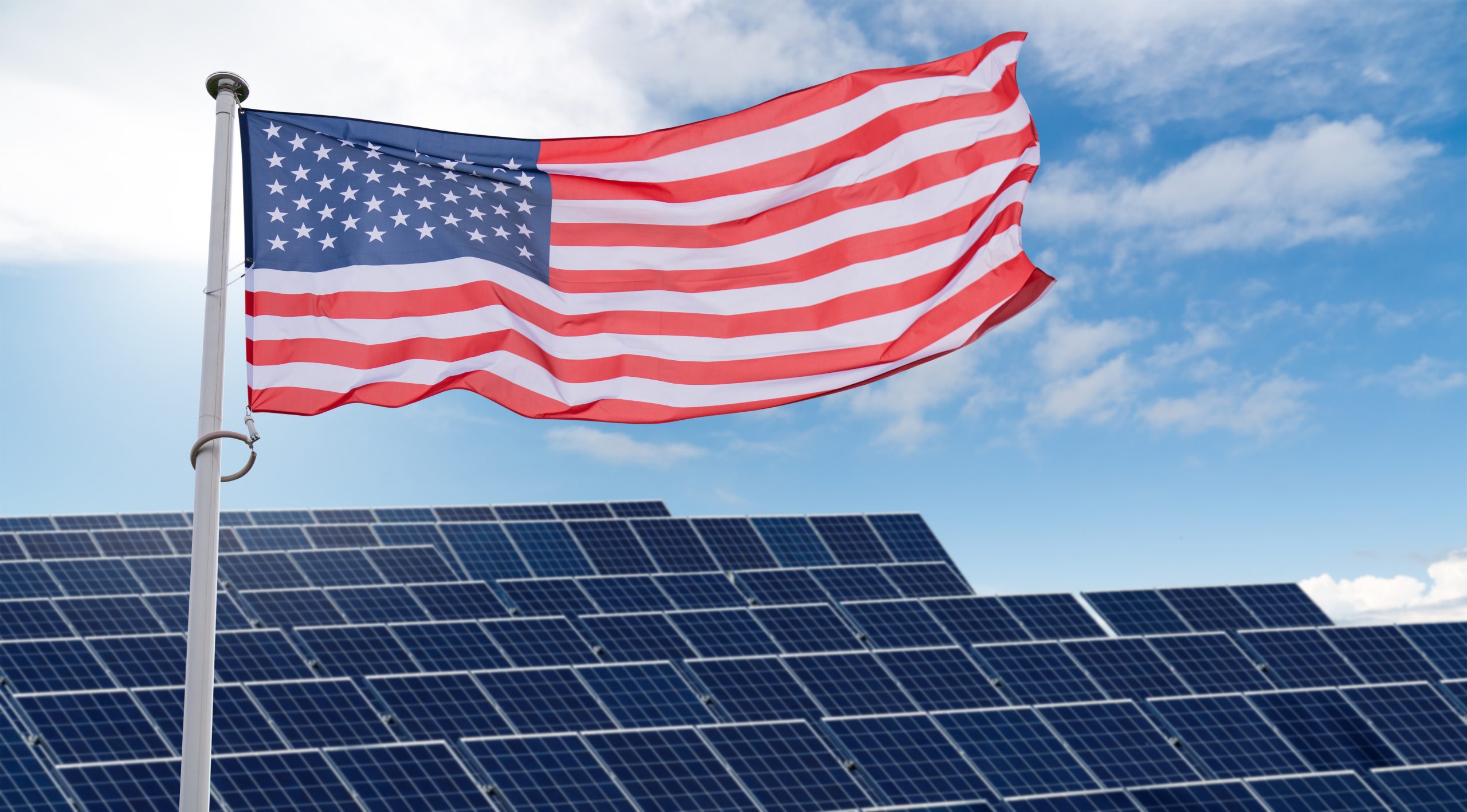 American flag flutters on the backgorund of solar panels. Symbol of sustainable development United States of America.